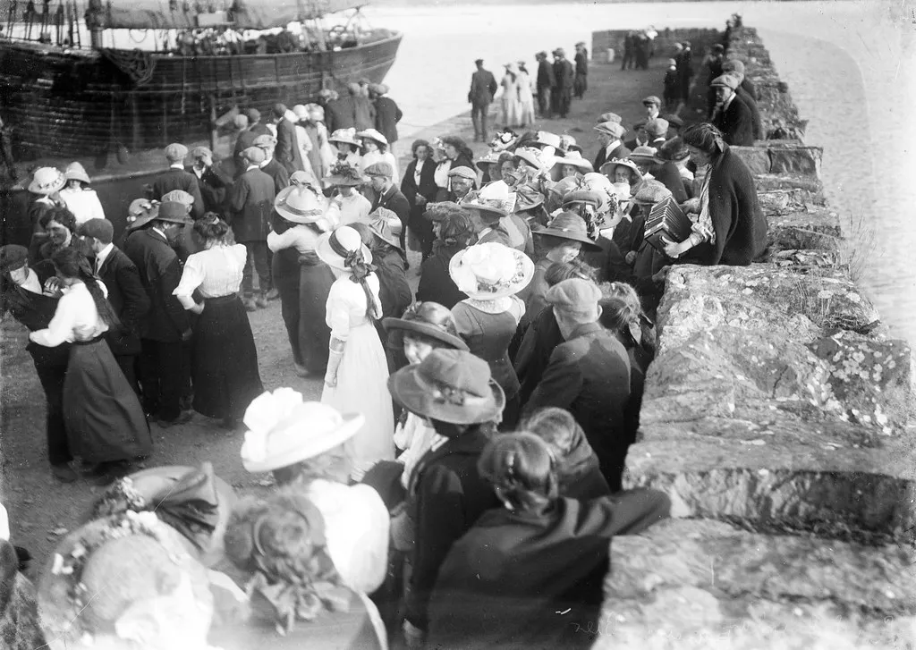 People dancing on a pier at the Kilmakilloge Pattern in County Kerry, 1913, with a melodeon player