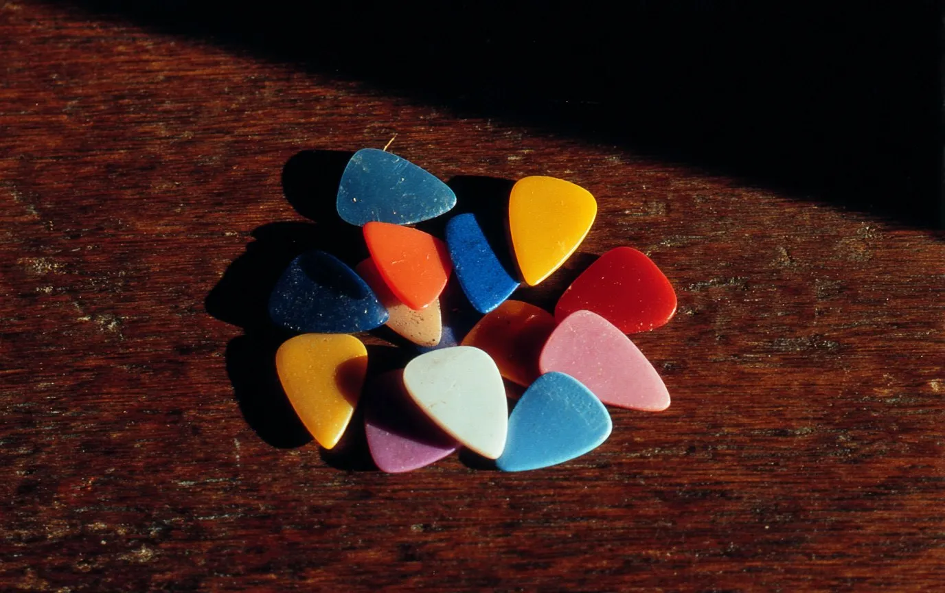 A scatter of plectrums of different gauges on a wooden table